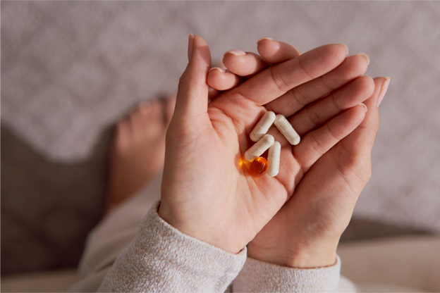 A woman holding supplements from the company Three International